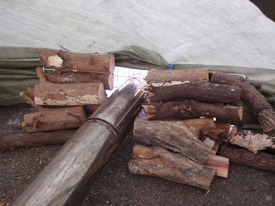 煙突とタープとの隙間を薪で塞ぐ